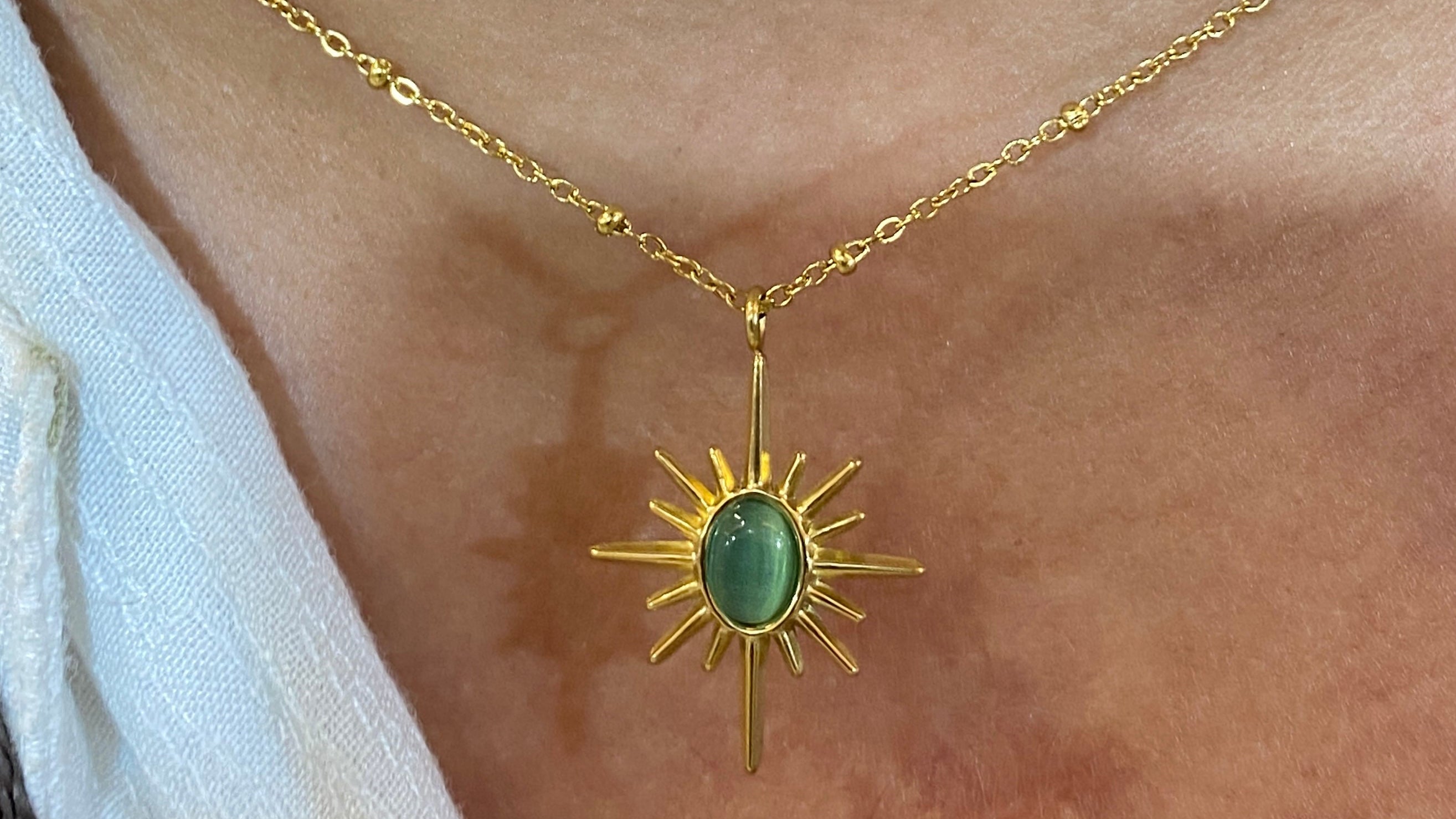 Gold necklace with a green pendant worn by a person